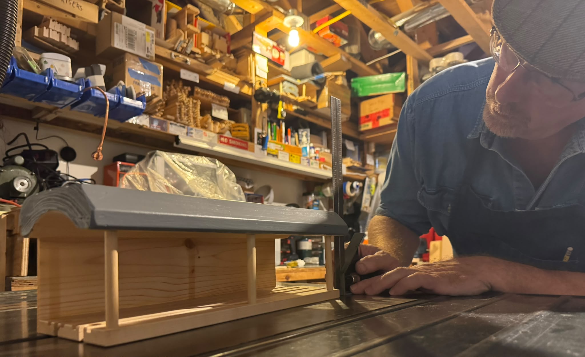 Mitch shaping a handmade wooden railway station in his workshop